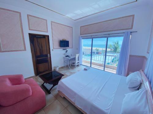 una camera da letto con un letto, un divano e una finestra di Hôtel Amazone a Cotonou