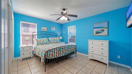 a blue bedroom with a bed and a ceiling fan at Coastal Retreat w Pool BBQ Sunset Views Beers and Sunshine by AvantStay in Port Aransas