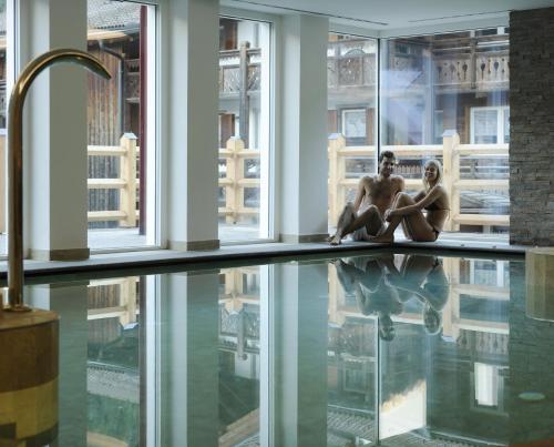 two women sitting on the edge of a swimming pool at Alpstyle Hotel Albolina Wellness & Beauty in Canazei