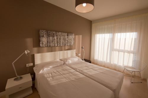 a bedroom with a white bed and a window at Apartamentos Irenaz in Vitoria-Gasteiz