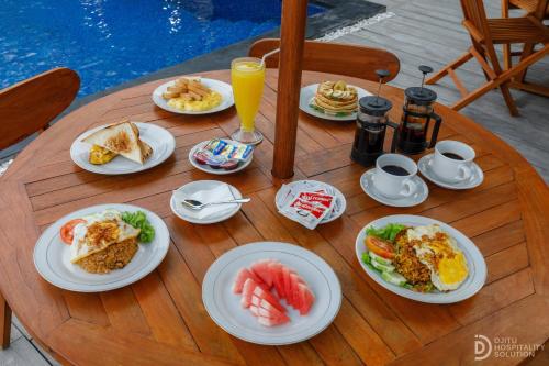 Una mesa de madera con platos de desayuno encima. en La Semaya Beach Villas, en Nusa Penida