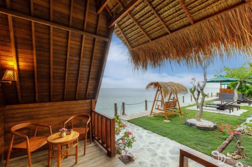 un porche de un complejo con mesa y sillas en La Semaya Beach Villas, en Nusa Penida