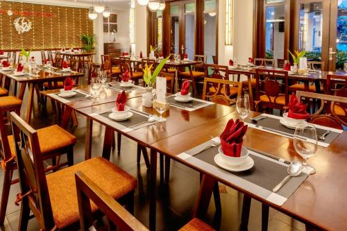 会安RiverTown Hoi An Resort & Spa的餐厅设有桌椅,并备有桑塔帽子