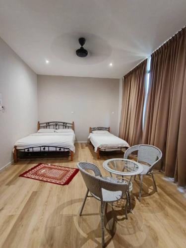 a room with two beds and a table and chairs at Homestay KNK in Tawau