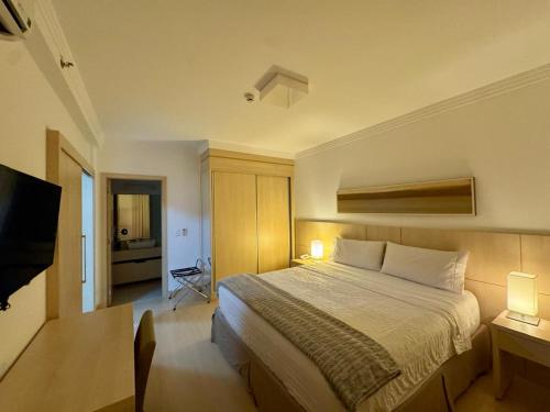 una habitación de hotel con una cama y un televisor en Flat Mont Blanc Premium, en Ribeirão Preto