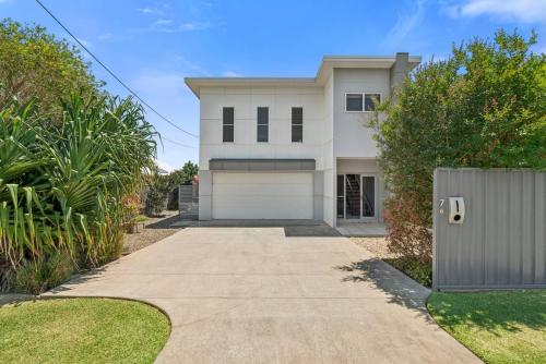 a large white house with a driveway at The Cheeky Palm - Beachy, enjoy a cheeky cocktail! in Woolgoolga