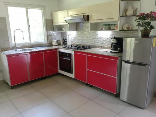 a kitchen with red cabinets and a stainless steel refrigerator at Ecotropicfarmhouse in Cerro Azul