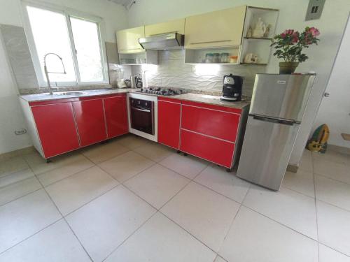 a kitchen with red cabinets and a stainless steel refrigerator at Ecotropicfarmhouse in Cerro Azul