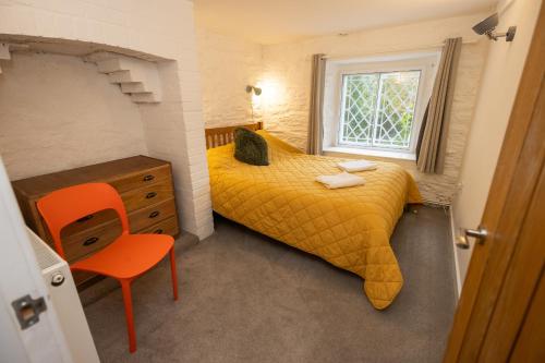 a small bedroom with a yellow bed and a window at The Coach House in Llangollen