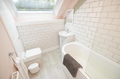 a bathroom with a tub and a toilet and a sink at The Coach House in Llangollen