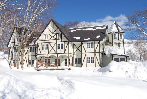 a large white house with snow on the ground at Henry in Niseko