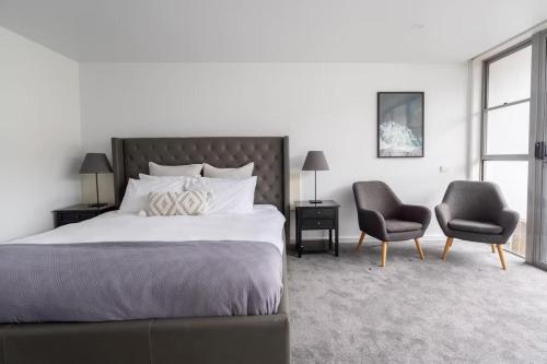a bedroom with a large bed and two chairs at Bay View Breeze in Lorne
