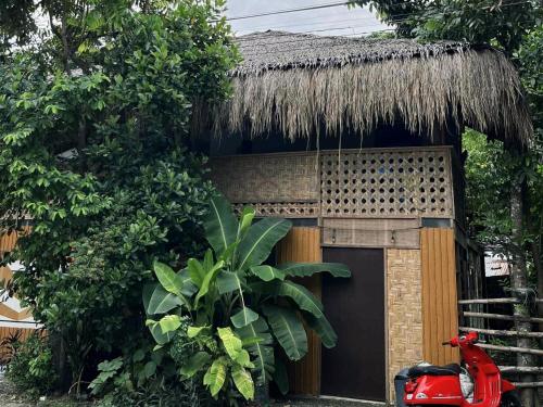 Balay Karajaw Island Home 12pax في جنرال لونا: منزل ذو سقف من القش ودراجة نارية حمراء متوقفة أمامه