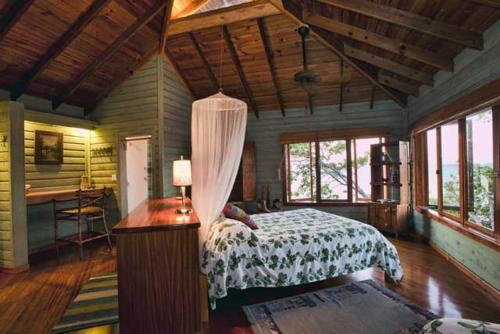 a bedroom with a bed and a desk and windows at Mariposa del Mar Oceanfront villa with private pool in Juticalpa