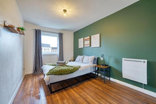 a bedroom with a bed and a green wall at New Slick Finnieston Pad w/ Free Parking in Glasgow