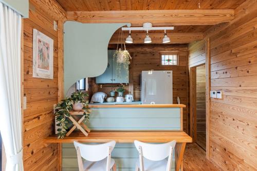 una cocina en una cabaña de madera con barra y sillas en AMANA Villa 101, en Amakusa