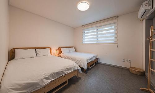 a bedroom with two beds and a window at Chuncheon Bali 376 in Chuncheon