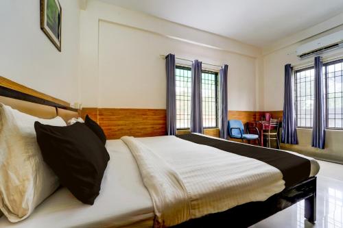 una camera da letto con un letto grande in una stanza con finestre di Hotel O Bharata Mata College Kakkanad a Kakkanad