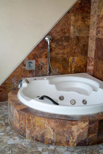 una bañera en una habitación con pared de piedra en Artisan Playa Esmeralda Family Beach Hotel, en Chachalacas