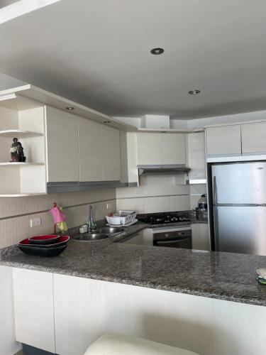 a kitchen with white cabinets and a granite counter top at Departamento Diamond Beach Tonsupa in Tonsupa