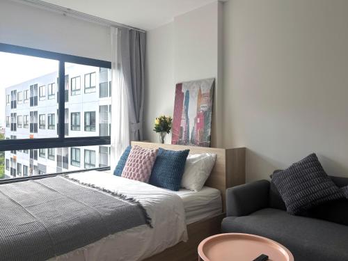 a bedroom with a bed and a couch and a window at MUXA&Vay in Pattaya North