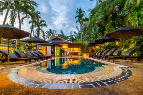 a pool at a resort with chairs and umbrellas at Bangtao Beach Chalet Resort in Bang Tao Beach