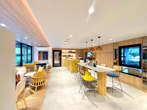 an open kitchen and dining room with yellow chairs and tables at MUXA&Vay in Pattaya North