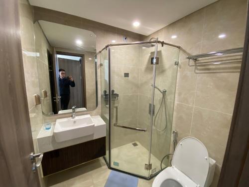 a man taking a picture of a bathroom with a shower at Hoàng Huy Commerce Võ Nguyên Giáp Enny Homestay in An Khê