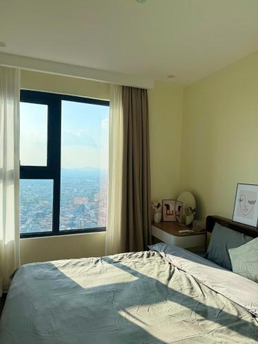 a bedroom with a bed and a large window at Hoàng Huy Commerce Võ Nguyên Giáp Enny Homestay in An Khê