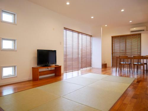 a living room with a flat screen tv and a table at Lulumalu AMAMI in Amami