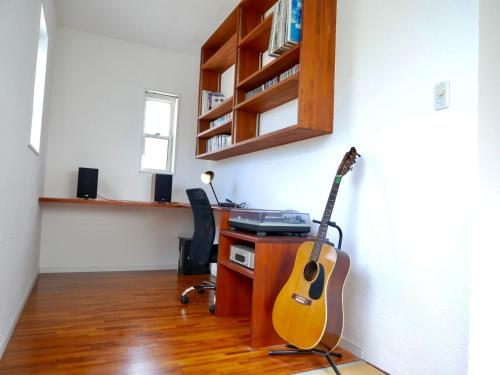 a room with a guitar and a desk with a keyboard at Lulumalu AMAMI in Amami