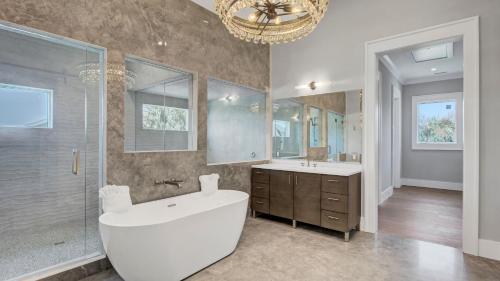 a bathroom with a tub and a sink and a chandelier at 3 47th Avenue by AvantStay Oceanfront Private Pool View in Isle of Palms