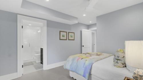 a white bedroom with a bed and a bathroom at 6 36th Avenue by AvantStay Stunning Private Pool in Isle of Palms