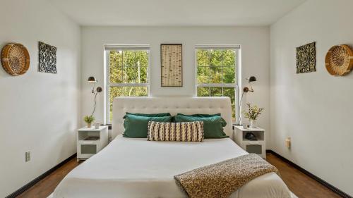 a bedroom with a large white bed with two windows at Mountain Mindset by AvantStay Pool Hot Tub Game Room Firepit in Long Pond