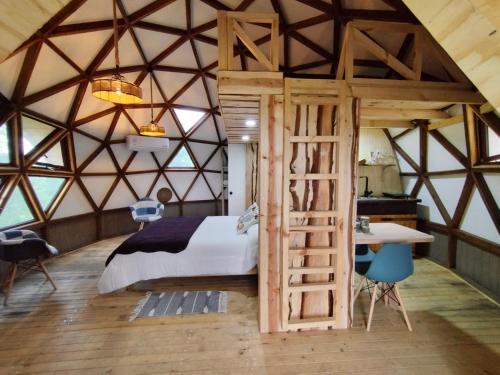 a bedroom with a bed and a desk in a room at Hostal y Domos Bello Horizonte in Villarrica
