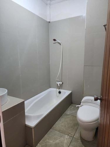 a bathroom with a toilet and a tub and a sink at kalaki beach hotel Bima in Daru