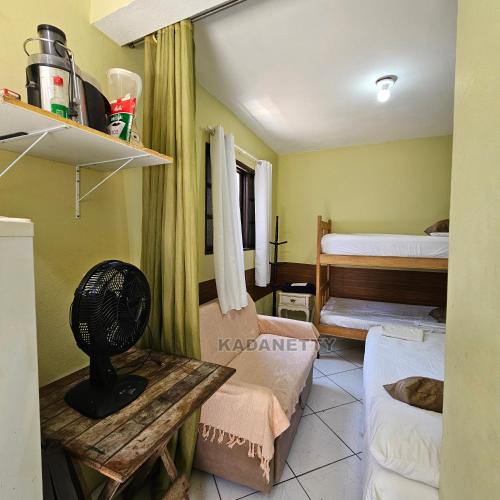 een kamer met 2 bedden en een tafel met een ventilator bij Casa Ventilada e Confortável, Perto da Rodovia e 2km da Praia in Caraguatatuba