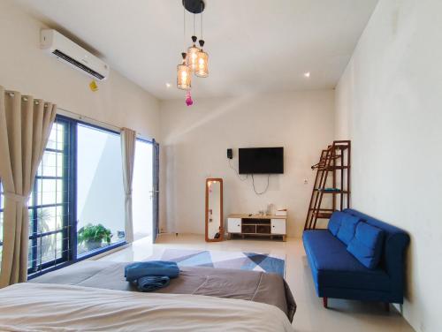 a bedroom with a bed and a blue couch and a tv at The Lavana Rumah Keboon in Mataram
