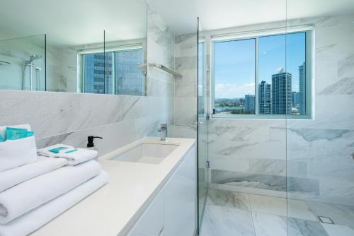 a white bathroom with a shower and a sink at The Waterford on Main Beach in Gold Coast