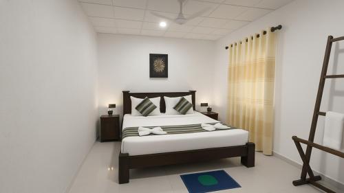 un dormitorio con una cama con sábanas y almohadas blancas en The Horizon Breeze, en Ahangama