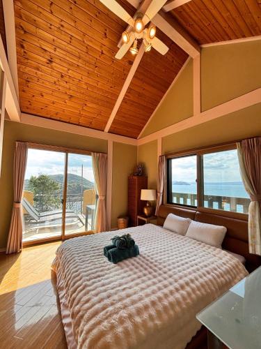 a bedroom with a large bed and large windows at AMANA ayurveda in Kami Amakusa