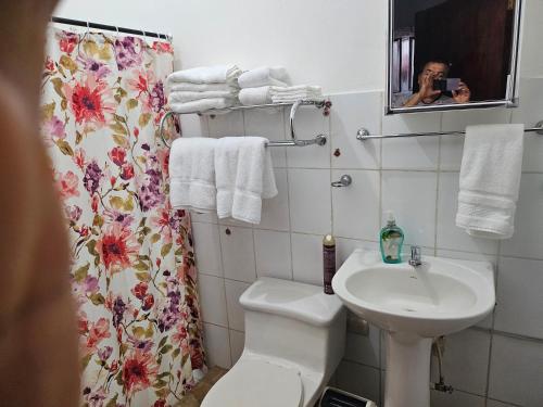 a bathroom with a toilet sink and a shower curtain at El hostal de Uriel in Izalco