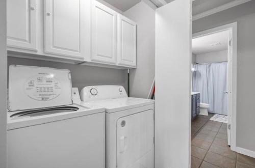 a kitchen with white cabinets and a washer and dryer at The Cove at Lake Hamilton in Hot Springs