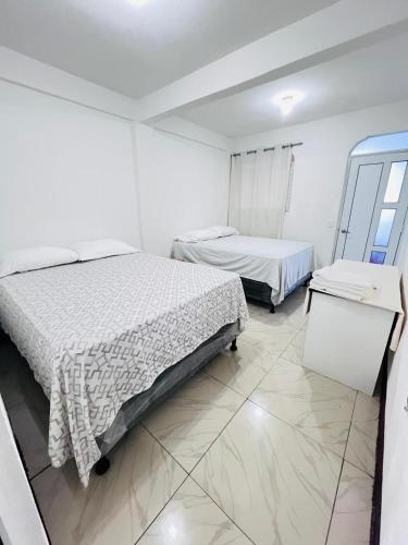 two beds in a room with white walls and tile floors at Hotel Julián Cotuc in San Juan La Laguna