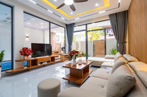 a living room with white furniture and large windows at Dâu Tây Villa in Da Nang