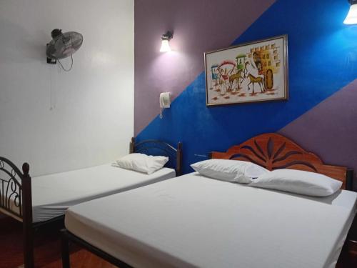 two beds in a room with a blue wall at OYO 1187 Rose And Ross Place Budget Hotel And Private Resort in Kabaong