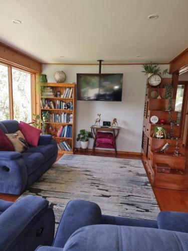 a living room with a couch and a tv at Queen Room with Balcony - Kookaburra Retreat Homestay in Pakenham