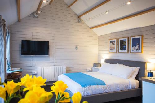 特魯羅的住宿－The cabin，一间卧室配有床和电视,并拥有黄色的鲜花