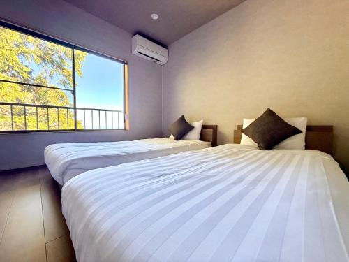 two beds in a room with a large window at Villa MAEUMー熱海絶景の棟貸しヴィラ BBQとペレットストーブ体験 最大13名追加料金なし in Atami