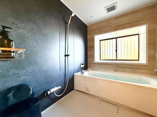 a bathroom with a tub and a sink and a window at Villa MAEUMー熱海絶景の棟貸しヴィラ BBQとペレットストーブ体験 最大13名追加料金なし in Atami